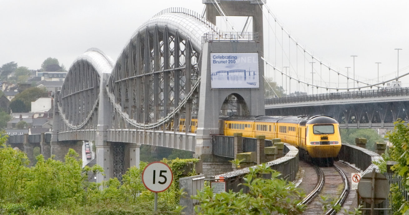 A yellow engineering train crosses the Royal Albert Bridge, daytime