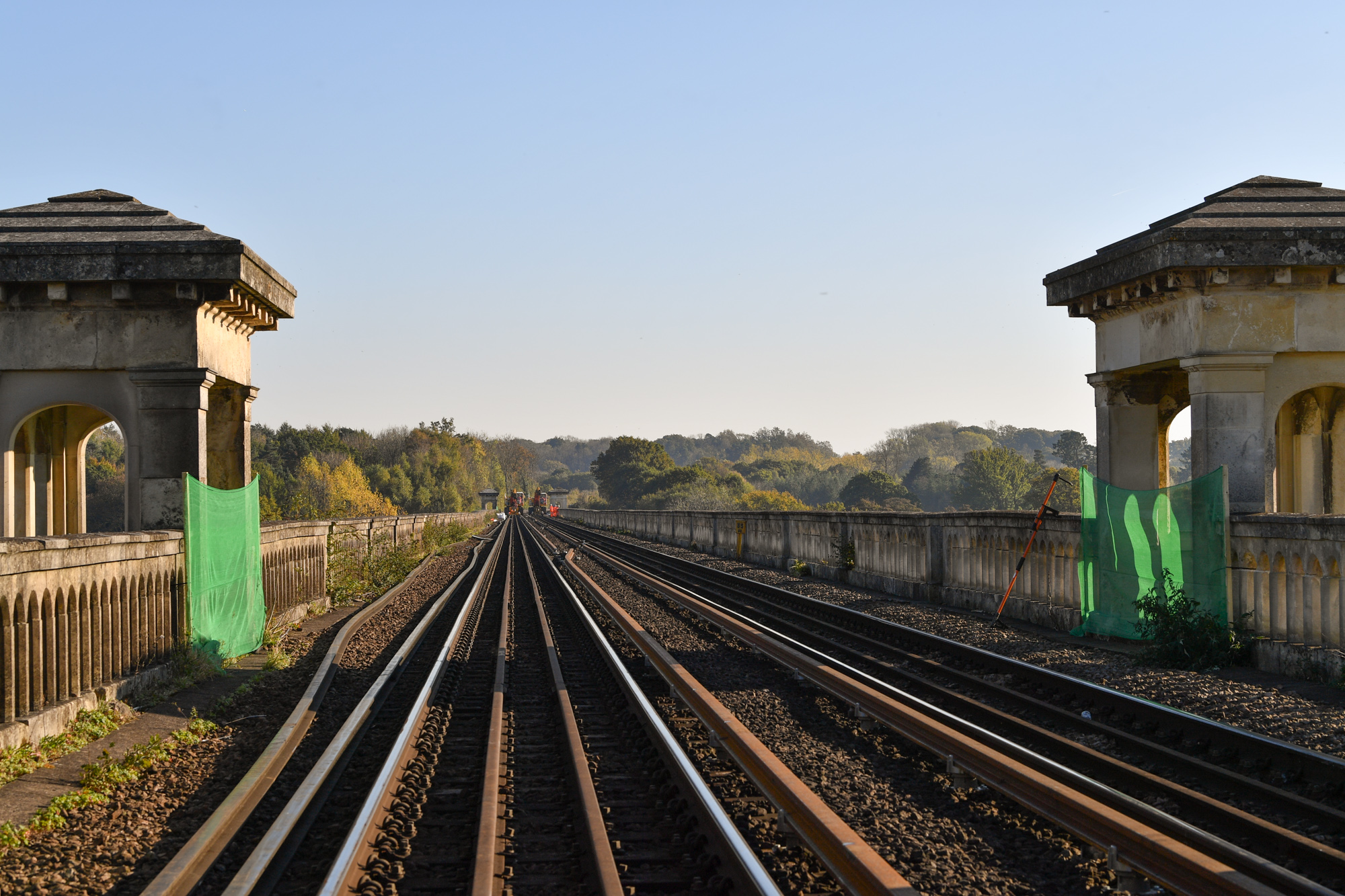 The golden hour on the tracks of the Brighton Main Line with historic pillars either side