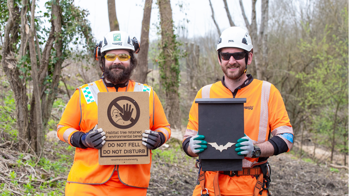 Arborists Chris Callaghan and ecologist Sam Jones with a bat box and sustainable warning sign.